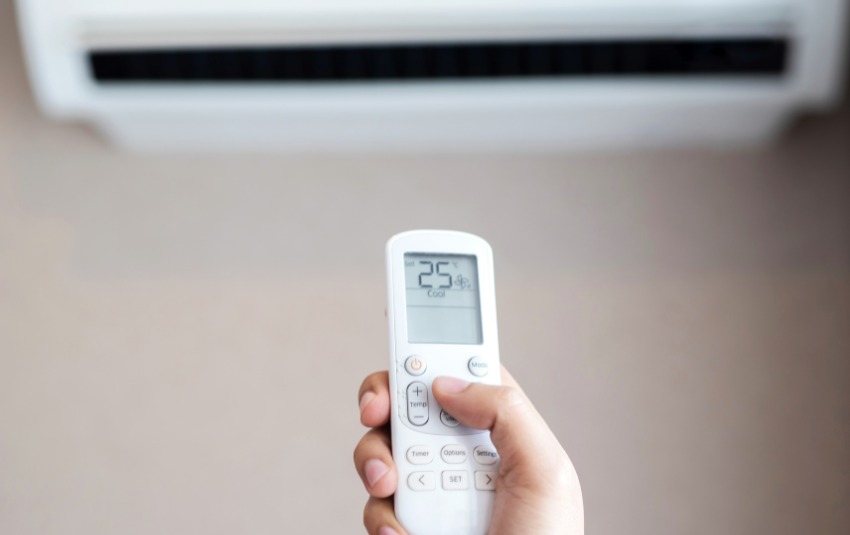 Person adjusting the air conditioning temperature using a remote